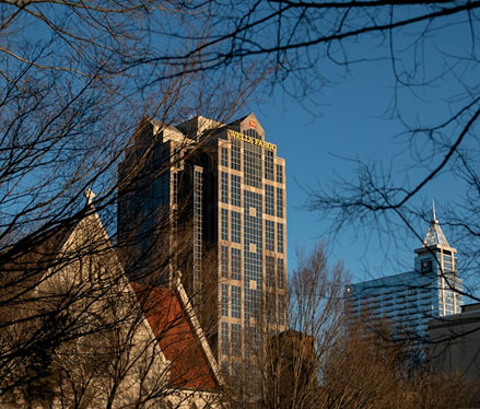 City buildings seen through leafless trees on a clear day.