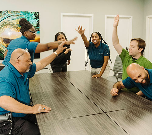 Pivotal Health team members high-fiving and laughing around a conference table